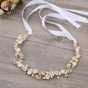 Détail d'un bandeau de mariée avec fleurs en nacre, perles et rubans de satin blanc