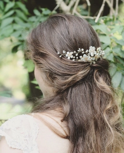 Close-up of bridal hair comb with white ceramic flowers and pearls on gold wire