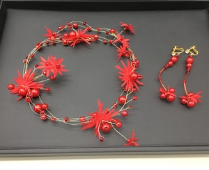 Macro view of bridal hairband and earrings set with red floral beads and gold wire
