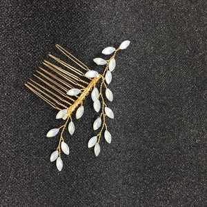 Détail du peigne de mariée avec fils dorés, feuilles d'opale et cristaux sur fond noir brillant