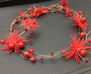 Detail of red fabric flowers and gold wire headband with pearls for bridal hairstyles