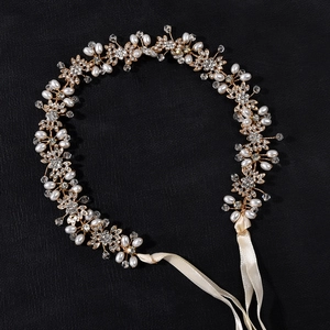 Dettaglio dell'accessorio sposa dorato con accenti in cristallo e perle su sfondo nero