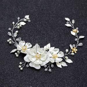 Détail d'un bandeau de mariée fait main avec fleurs en satin blanc et feuilles argentées
