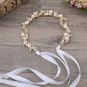 Gros plan du bandeau de mariée avec fleurs, perles et strass sur fond bois sombre