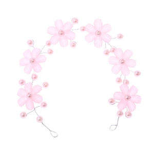Détail de pétales de fleurs roses givrées et perles sur un bandeau de mariée souple