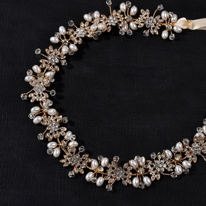 Dettaglio fascia da sposa con fiori dorati, perle bianche e cristalli scintillanti