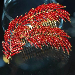 Elegant gold-tone feather hair comb encrusted with vibrant red rhinestones on a sleek black base