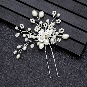 Détail d'une épingle à cheveux de mariée avec pétales blancs, perles et cristaux brillants
