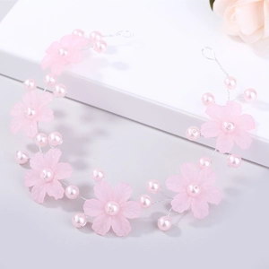 Détail de fleurs roses mates et perles sur un bandeau de mariée en fil de métal tissé