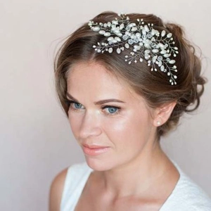 Elegant silver bridal hair vine with white pearls and crystals worn on soft bun hairstyle