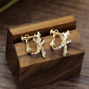 Macro shot of golden starfish clip-on earrings with sparkling white crystals on wood