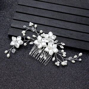 Handmade bridal hair comb with silver wire flowers, pearls, and crystals on a dark background
