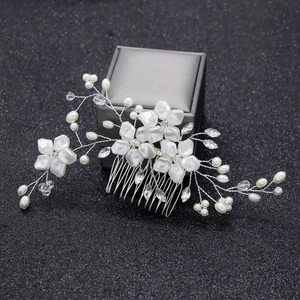 Close-up of bridal hair comb with white pearl flowers and crystals on dark box