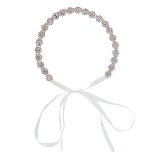 Détail macro du bandeau de mariée en cristal avec base dorée et rubans de satin blanc