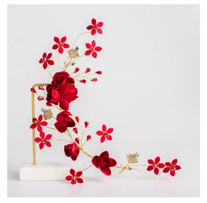 Eleganter Braut-Haarschmuck mit roten Satinrosen und Golddraht auf Marmorständer