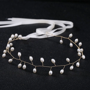Close-up of handmade pearl headband with gold wire branches and white satin ribbon ties