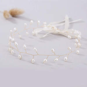 Close-up of handmade pearl vine hairpiece with gold wire and white satin ribbons