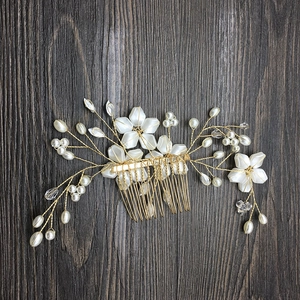 Macro shot of gold wedding hair comb with white flowers and handmade pearls decoration