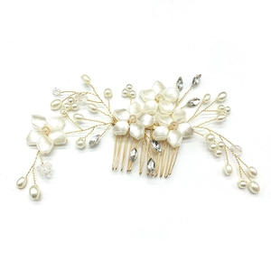 Close-up of handmade bridal hair comb with gold wire, white flowers, pearls and crystals