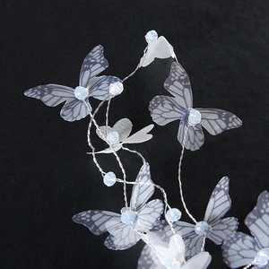 Détail de la pince à cheveux papillon en organza et perles bleues sur fond en velours noir