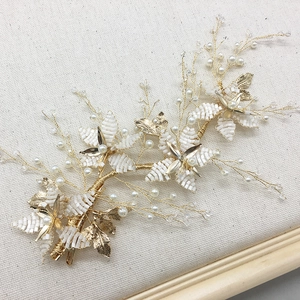 Close-up of handmade bridal hair comb with gold wires, white pearls and floral beads