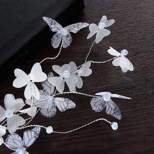 Barrette papillon blanche avec ailes en tulle et perles bleues sur fond en bois
