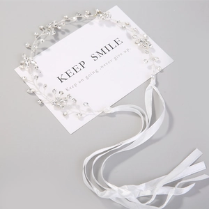 Close-up of handmade bridal headband with silver vines, sparkling crystals and white ribbon