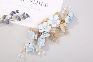 Détail du peigne de mariée avec fleurs en tissu bleu, feuilles dorées et strass