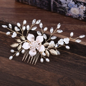 Elegant pearl bridal hair comb with gold flowers and leaves on a vintage wood surface