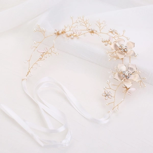 Detail von Brauthaarschmuck mit goldenen Blumen, Perlen und Kristallen auf Spitze