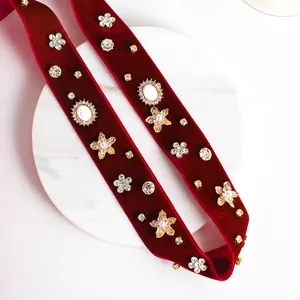 Elegant red velvet bridal headband with gold flowers and cameo on marble tray