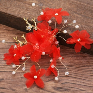 Détail de pinces à cheveux de mariée avec fleurs en tissu rouge, fils dorés et perles