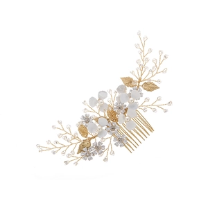 Détail d'un peigne à cheveux fait main avec fleurs blanches, fils dorés et cristaux