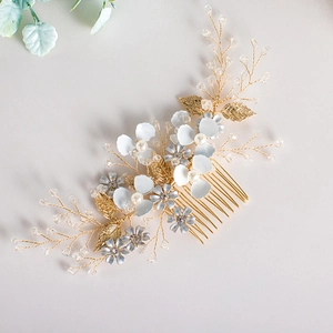 Détail du peigne de mariée avec fleurs en émail blanc, feuilles dorées et cristaux bleus