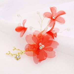 Détail de pinces à cheveux de mariée avec fleurs en maille rouge et branches dorées