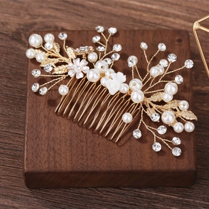 Elegant gold bridal hair comb with pearls, crystals and floral detail on wood