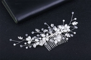 Exquisite silver bridal hair comb with pearls, crystals and metallic leaves on black surface