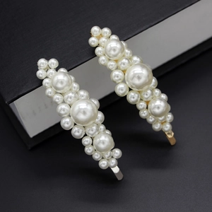 Primer plano de elegantes horquillas con perlas de marfil sobre bases de metal oro y plata