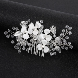 Close-up of white resin flowers and crystal beads on a bridal silver hair comb detail