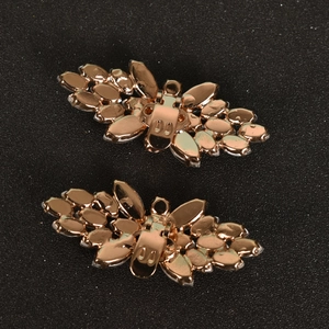Makroaufnahme von roségoldenen Schmetterlings-Schuhclips mit Metallverschluss auf dunklem Grund