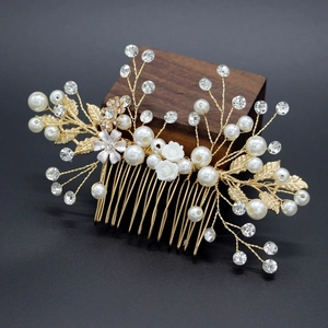 Close-up of handmade bridal hair comb with pearls, crystals and resin flowers on gold wire