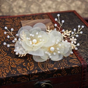Dettaglio dell'accessorio per capelli da sposa con fiori di organza e perle dorate