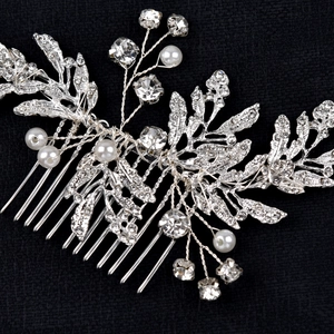 Macro shot of bridal hair comb with silver leaves, white pearls and sparkling rhinestones