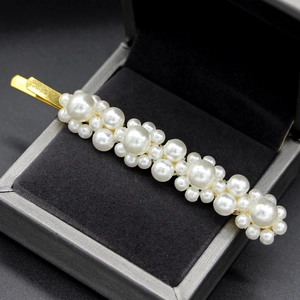 Detalle de pasador de perlas con diseño floral sobre una base de metal dorado