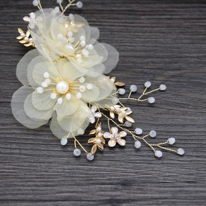 Dettaglio del fermaglio sposa con fiori in rete e perle bianche su fondo di legno