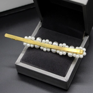 Detalle de horquilla de perlas coreana con base de metal dorado en caja de joyas