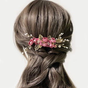 Détail du peigne à cheveux avec fleurs roses et feuilles dorées dans un chignon élégant