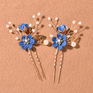 Detail of blue floral hair pins with rhinestones, gold leaves and pearls on brown felt