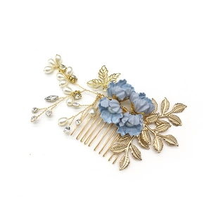 Eleganter goldener Braut-Haarkamm mit blauen Stoffblumen und Perlen auf weißem Hintergrund