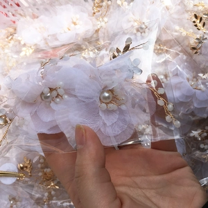 Dettaglio di accessorio per capelli in chiffon bianco fatto a mano con perle e filo d'oro